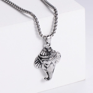 Close-up of a silver elephant head pendant on a box chain over a white display cube