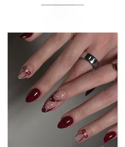 Détail de faux ongles amande bordeaux et rose avec nœuds 3D et perles élégantes