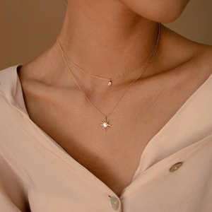 Close-up of a layered gold necklace featuring an eight-pointed star and zircon pendant