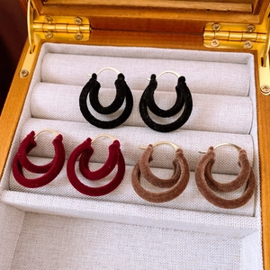 Detailed view of three pairs of velvet hollow hoop earrings in black, red, and brown colors