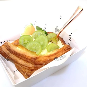 Close-up of Danish pastry with fresh grapes and rose gold dessert fork in paper tray