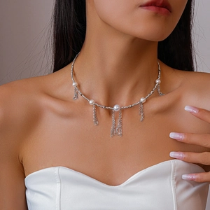 Close-up of silver chain necklace with pearls and elegant metal fringe tassels