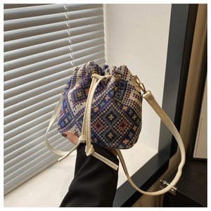 Detail of woven bucket bag featuring blue geometric patterns and white leather drawstring