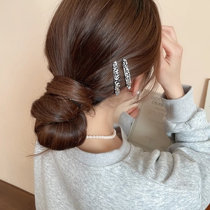 Dettaglio di due fermagli per capelli maculati e una collana di perle indossati