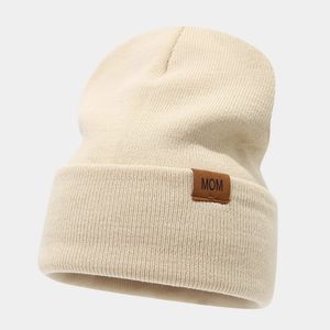 Close-up of knit beanie with brown leather MOM patch detail and soft ribbed texture