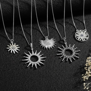 Detailed view of silver sun pendants with cubic zirconia on black leather background