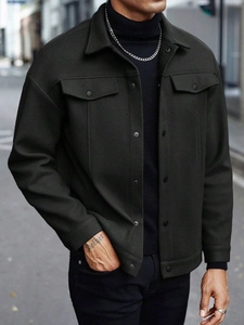 Detail of dark charcoal overshirt featuring snap chest pockets and metallic buttons