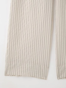 Close-up of beige cotton-linen striped trousers showing fine double stitching on the hem