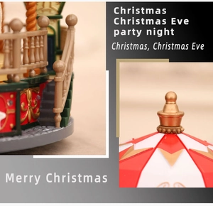 Detail of Christmas carousel music box showing the golden fence and festive red top ornaments