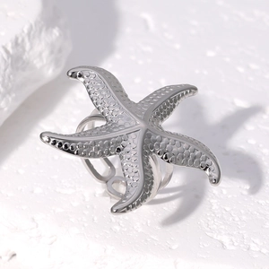 Macro detail of silver starfish open ring with textured surface on white mineral stone
