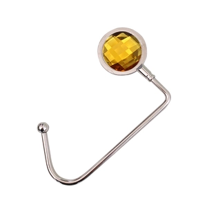 Close-up of portable desk bag hook with a round yellow crystal and silver metal finish