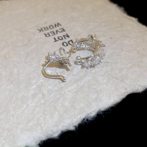 Close-up of silver zircon ear cuff set with heart and star patterns on textured paper
