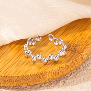Macro view of minimalist silver bubble ring on a natural bamboo base with beige silk