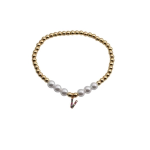 Detail of beaded gold bracelet with white pearls and a colorful zircon letter V charm