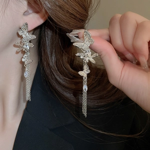 Detail of silver butterfly tassel earrings with sparkling teardrop zircons on model