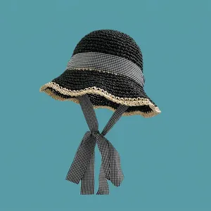 Detailed close-up of a woven straw bucket hat featuring a chic gingham bow and ribbon