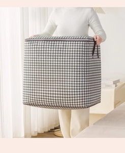 Close-up of large houndstooth storage bag with handles and zipper being held by hand
