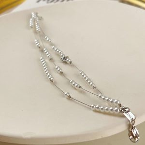 Pulsera de tres capas de perlas con dijes de estrellas plateadas y cierre ajustable
