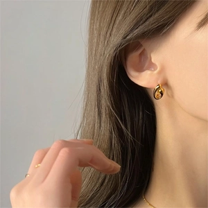 Close-up of minimalist gold twisted knot earrings worn by a model in a studio setting