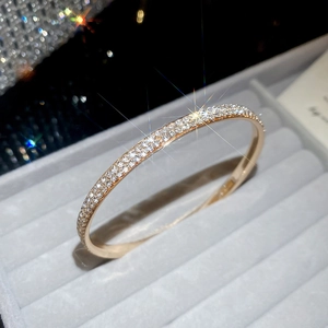 Close-up of golden three-row crystal paved bangle in a grey velvet jewelry box