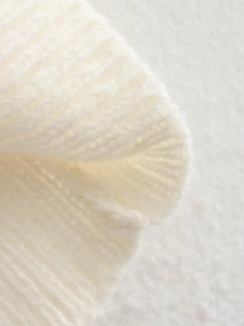 Gros plan de la maille épaisse blanc crème montrant la texture côtelée et le fil doux