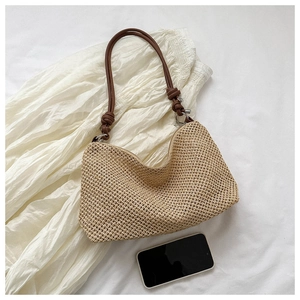 Detail of khaki handmade woven straw tote with brown leather strap and intricate texture