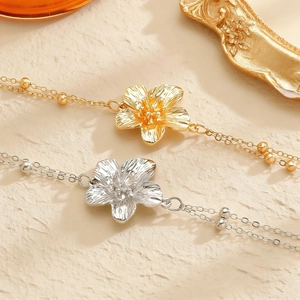 Detail van boheemse frangipani bloem lichaamsketting in goud en zilver met metalen kralen