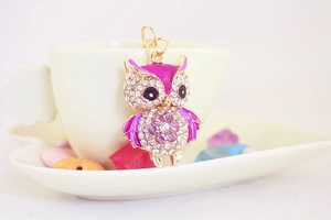 Close-up of golden owl keychain with purple enamel and sparkling crystal rhinestones