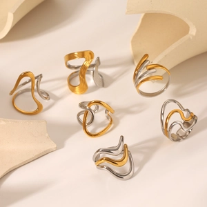 Detail of two-tone gold and silver irregular geometric rings on a minimalist background
