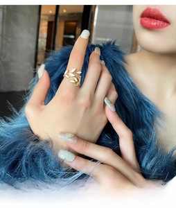 Close-up of golden leaf open ring on model with white decorative elements and blue coat