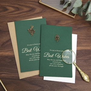 Vintage green greeting cards with metal charms and envelopes on dark wood desk