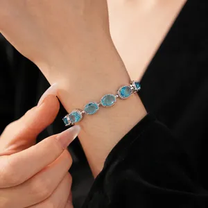 Elegant silver bracelet featuring oval light blue zircons on female wrist