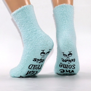 Close-up of non-slip letters and wine glass icon on fuzzy blue coral fleece socks