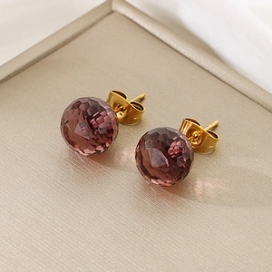 Macro view of mauve faceted crystal glass ball earrings with golden titanium steel studs