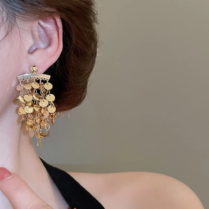 Close-up of golden multi-layer round sequin tassel earrings worn by a model in soft light