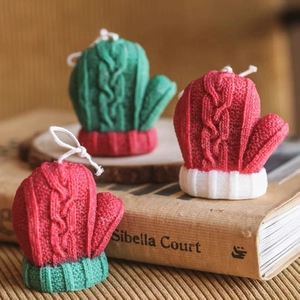 Three knitted glove shaped candles with realistic textures in festive red and green colors