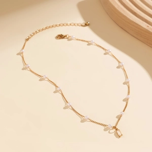 Macro detail of golden chain necklace with pearls and rectangular clear crystal pendant