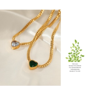 Detail view of heart-shaped crystal pendants on gold flat snake chains over silk fabric