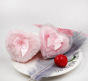 Detail of heart-shaped plush powder puffs and clear storage case on white plate