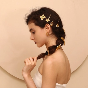 Detailed view of model wearing a set of 18K gold-plated wing shaped hair accessories