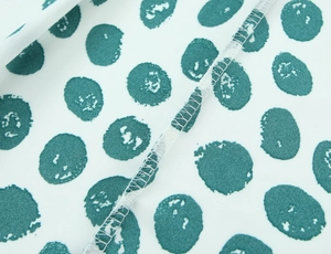 Macro detail of white and turquoise polka dot chiffon fabric with stitched seam edges