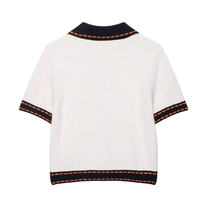 Detail of white knit top with navy blue ribbed edges and orange geometric patterns
