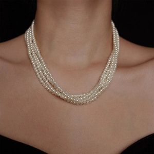 Dettaglio elegante collana di perle multistrato su modella con design francese chic