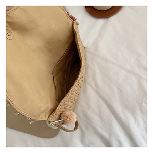 Close-up of handmade straw bag showing interior pocket structure and tassel detail