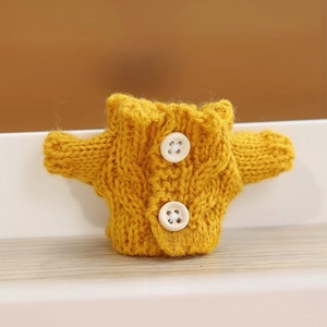 Close-up of yellow knitted doll cardigan with white buttons and rib collar detail
