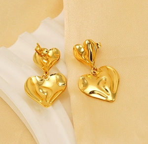 Vue macro de boucles d'oreilles double cœur dorées avec un design en métal fluide