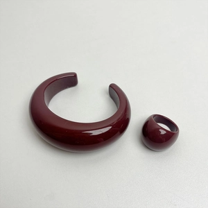 Detail of wine red resin bangle and thick ring set with high glossy finish in minimalist style