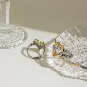 Bague cœur bicolore or et argent présentée sur un décor en verre élégant