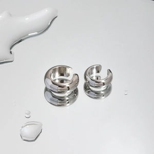 Macro shot of silver C-shaped polished stainless steel ear cuffs on a water surface