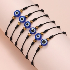 Detail of six woven Evil Eye bracelets with blue resin beads on a display stand